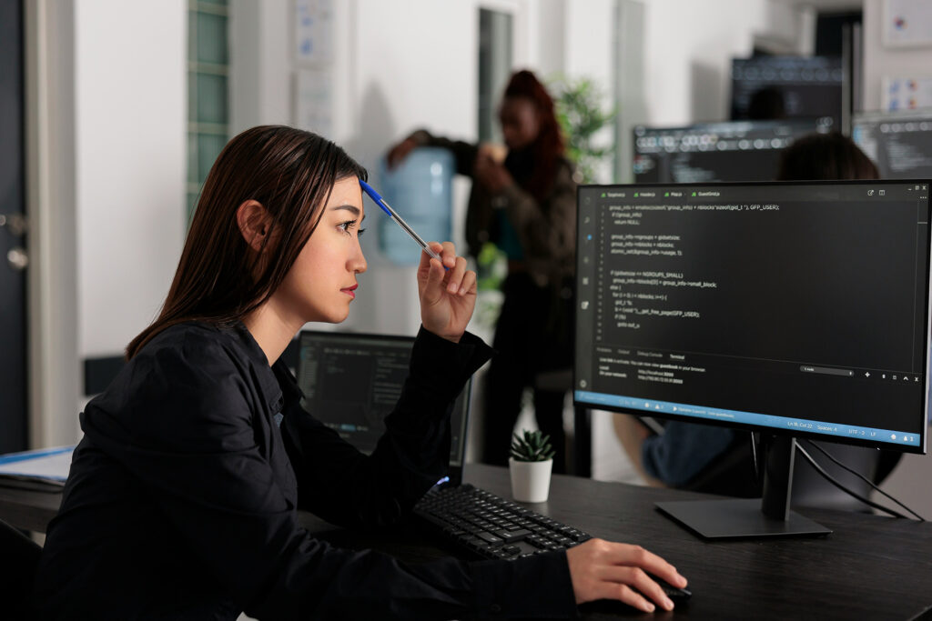 Profissional analisando código em monitor no escritório, representando o desenvolvimento de habilidades técnicas valorizadas pelo mercado na era da IA
